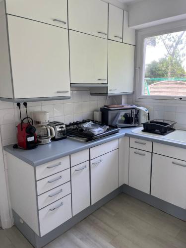 une cuisine avec des armoires blanches et un comptoir dans l'établissement Maison des dunes proche plage, à Quiberon