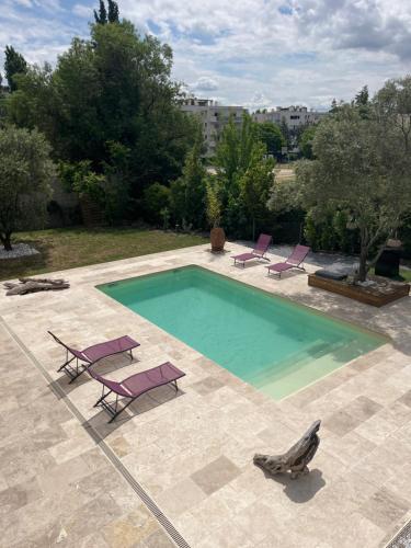 a swimming pool with two lounge chairs at Location Appartement saisonnier in Clermont-lʼHérault