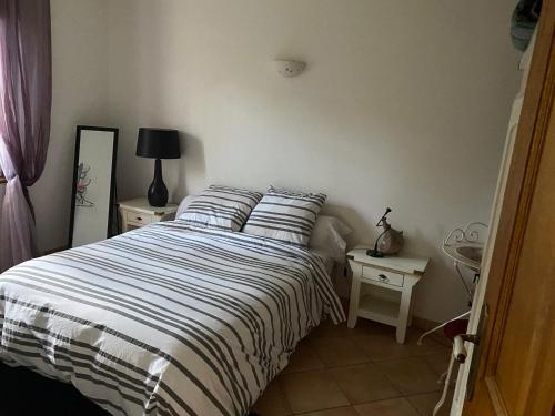 塞里尼昂-迪孔塔的住宿－Studio bord de piscine，一间卧室配有带条纹被子的床