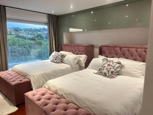 a bedroom with two beds and a large window at Amazing! 7 bedroom villa with rooftop pool & views in Cape Town