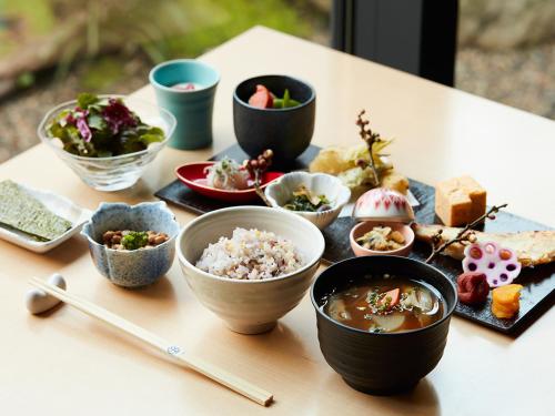 a table with bowls of food on a table with chopsticks at ONSEN RYOKAN YUEN SHINJUKU in Tokyo