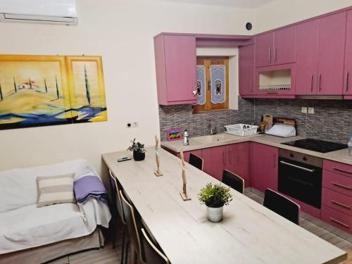 una cocina con armarios rosas y una mesa con plantas en Alba Traditional Countryhouse New Anchialos village en Néa Ankhíalos