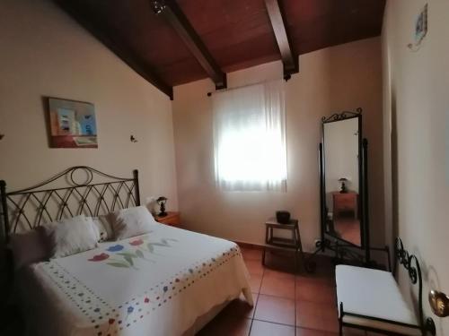 1 dormitorio con cama, espejo y ventana en La casita de la abuela isabel, en Ubrique