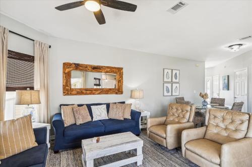 uma sala de estar com sofás azuis e uma ventoinha de tecto em Sandpiper Cove 9232 condo em Destin