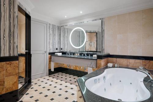 baño grande con bañera y espejo en Tbilisi Marriott Hotel, en Tiflis