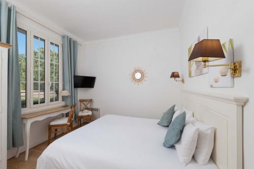 a white bedroom with a bed and a window at Hôtel Beau Site - Cap d'Antibes in Antibes
