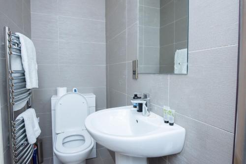 a white bathroom with a toilet and a sink at Evergreen Apartments-Flat 5, London in London