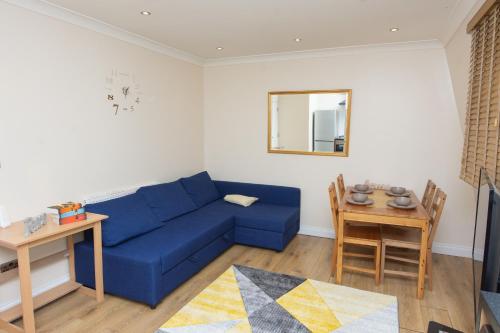a living room with a blue couch and a table at Evergreen Apartments-Flat 5, London in London
