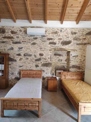 duas camas num quarto com uma parede de pedra em Alexander's cottage em Límni