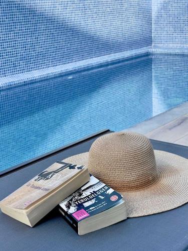 a hat and a book next to a swimming pool at The Retreat Fuseta - 3 bed eco villa, own pool in Fuzeta