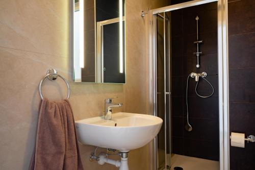 a bathroom with a sink and a shower with a mirror at The Address Seafront Suites with Hot Tub in Pieta