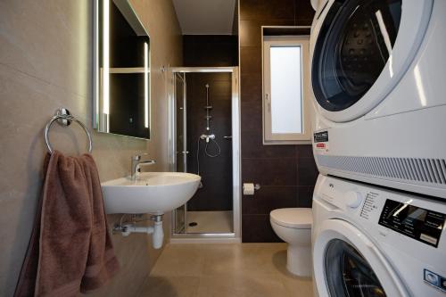 a bathroom with a sink and a washing machine at The Address Seafront Suites with Hot Tub in Pieta