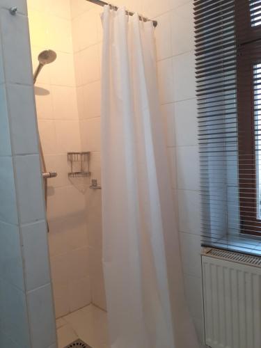 y baño con ducha con cortina blanca. en Martinsgarten, en Angermünde
