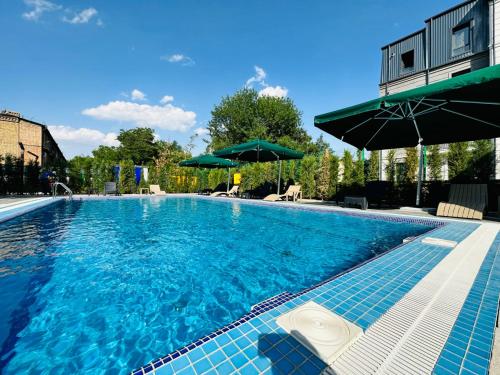 a large swimming pool with blue tiles and umbrellas at RICH PARK HOTEL in Tashkent