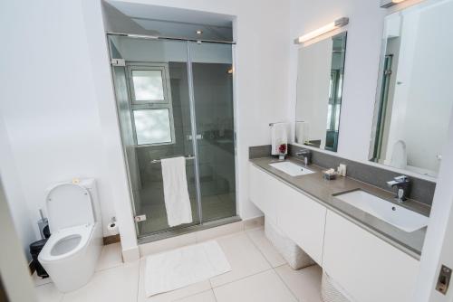 een badkamer met een toilet, 2 wastafels en een douche bij Summer Breeze - Beachfront - 3 Bedrooms Suite in Pointe d'Esny