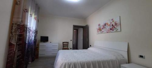 a white bedroom with a bed and a dresser at B&b Il Giardinetto in Selargius