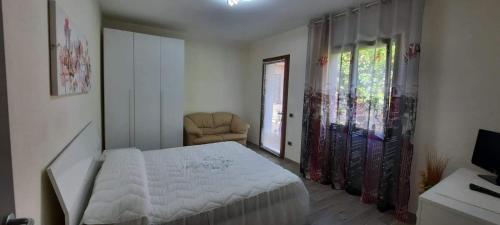 1 dormitorio con 1 cama blanca y 1 silla en B&b Il Giardinetto, en Selargius