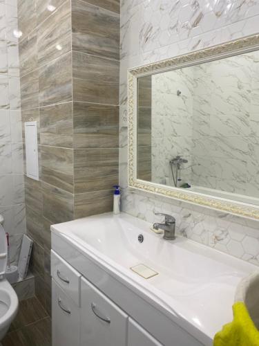 a bathroom with a white sink and a mirror at Жк Абырой Ризеденс in Atyrau