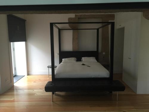 a bed in a room with a black frame at Solar Do Castelo - Melgaço in Melgaço