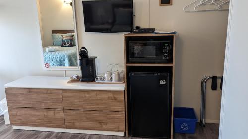 a small kitchen with a microwave and a refrigerator at Motel Gentilhommière in Saint-Siméon