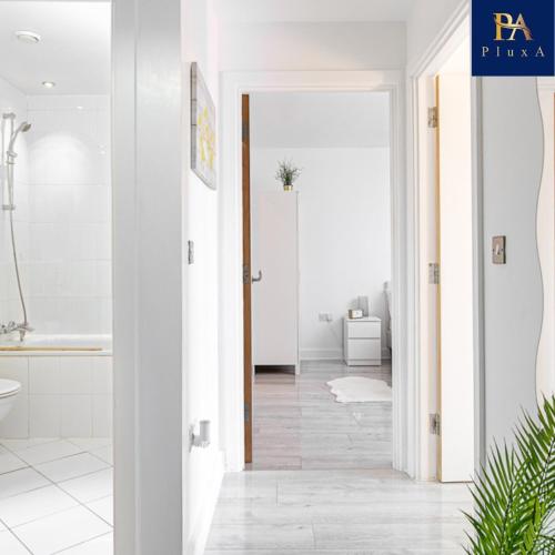 a hallway with a bathroom with white walls and white floors at Pluxa Waterside Apartment - Stylish 2bathrooms, walk to transit in Birmingham