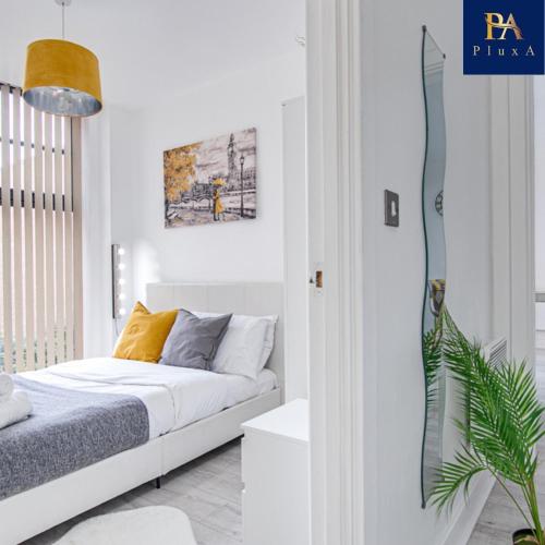 a white bedroom with a bed and a plant at Pluxa Waterside Apartment - Stylish 2bathrooms, walk to transit in Birmingham