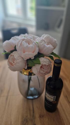 a vase filled with pink flowers next to a bottle at Alfama Garden in Grudziądz