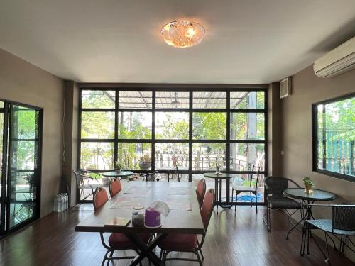 a dining room with a table and chairs and windows at V Tharm Hotel in Udon Thani