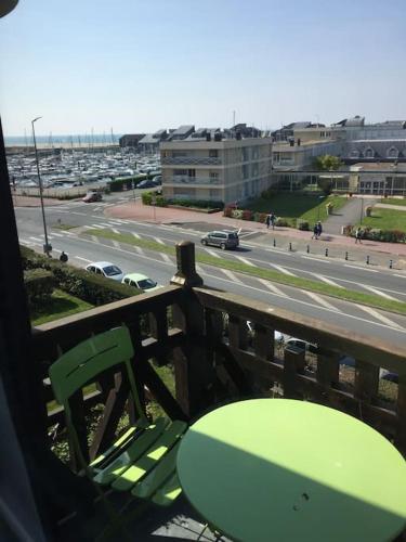 un banc vert sur un balcon avec vue sur la ville dans l'établissement Les Embruns - Le Balcon - 2eme Etage, à Deauville