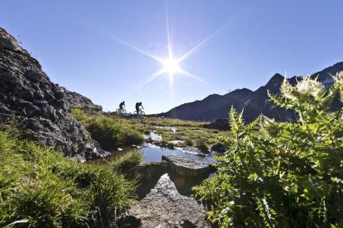 a group of people riding bikes on a hill with a cross in the sky at Pension Wendlhof in Obergurgl