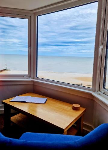 a table in front of a window with a view of the beach at The Wave - 3 bed beach front home in Sheringham in Sheringham