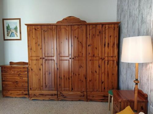 um grande armário de madeira num quarto com um candeeiro em Fly Dodo Summer Residence em Marsaskala