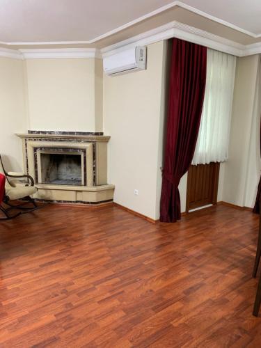 an empty room with a fireplace and a red curtain at esa house in Kireçhane