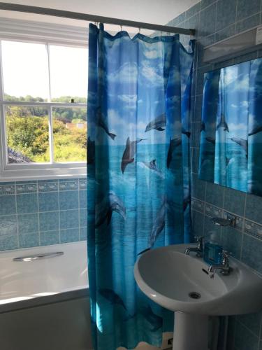 a bathroom with a sink and a shower curtain with dolphins at No 52 bed and breakfast in Helston