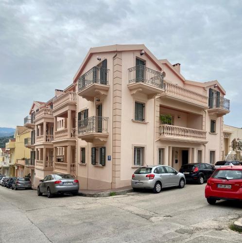 un grande edificio rosa con auto parcheggiate in un parcheggio di Valeria's Apartment ad Argostoli