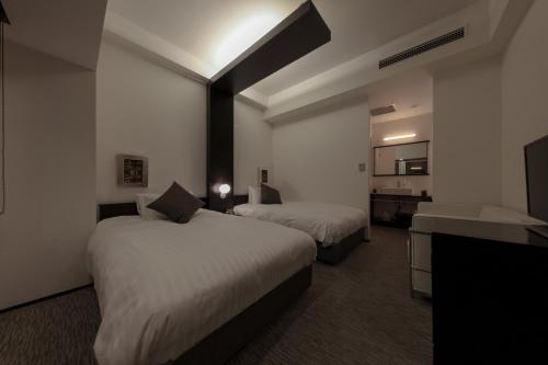 a hotel room with two beds and a television at Furano Natulux Hotel in Furano