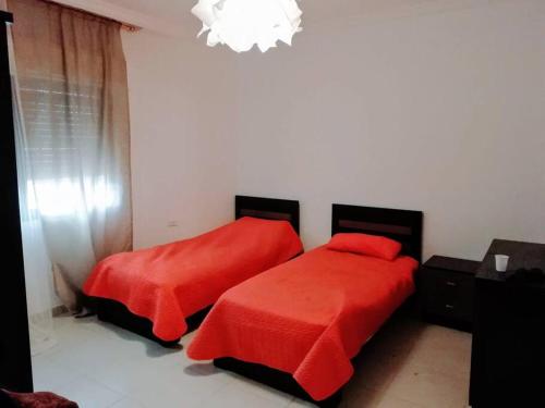 um quarto com 2 camas com lençóis vermelhos e um lustre em Apartment with terrace garden em Amã