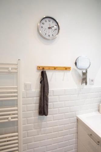 La salle de bains est pourvue d'une horloge murale. dans l'établissement Maison village - 7 min de Metz centre, à Lessy