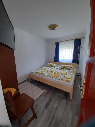 a small bedroom with a bed and a chair at Budapest Vendégház in Tiszafüred