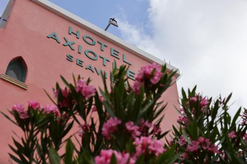 a pink building with a sign on it with pink flowers at Axiothea Hotel in Paphos City