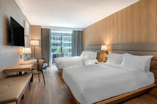 ワシントンにあるAC Hotel by Marriott Washington DC Convention Centerのベッド2台とデスクが備わるホテルルームです。