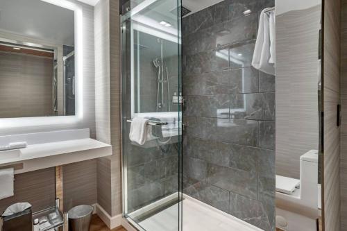 a bathroom with a glass shower and a sink at AC Hotel by Marriott Washington DC Convention Center in Washington, D.C.