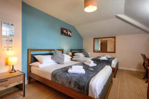 a bedroom with two beds and a mirror at The Victoria Inn in Truro