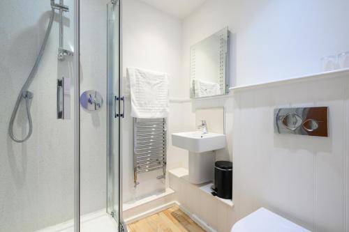 a white bathroom with a shower and a sink at The Victoria Inn in Truro