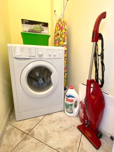a washing machine with a red vacuum cleaner next to it at Sunny Apartment Amaliada in Amaliás