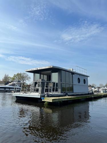 a house boat sitting on a dock in the water at Stoere HOUSEBOAT op toplocatie! in Belt-Schutsloot