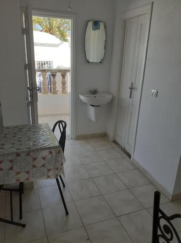 ein Esszimmer mit einem Tisch und einem Waschbecken in der Unterkunft Appartement S2 bien équipé à Hammamet centre (200m de la plage) in Hammamet