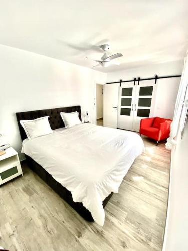 サン・フェルナンドにあるApartamento en el centro San Fernando Cadiz.のベッドルーム(白いベッド1台、赤い椅子付)