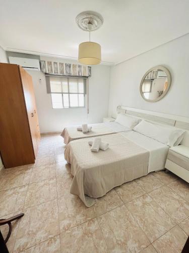 a white bedroom with two beds and a mirror at Apartamento El Arenal - Free Parking in Córdoba