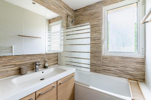 uma casa de banho com um lavatório, uma banheira e uma janela em Appartement tout équipé em Marselha